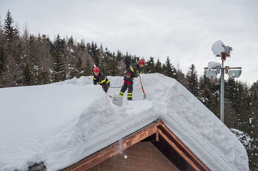 Two Workers removing heavy snow from roof