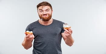 Man with grin, cupcakes in both hands and frosting on his face