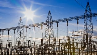 An electrical power grid with the sun shining and blue sky