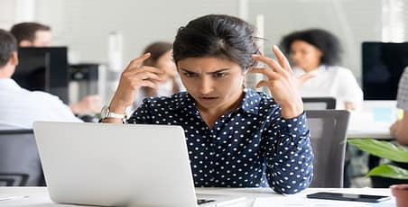 Woman sitting in front of computer with a frustrated look on her face