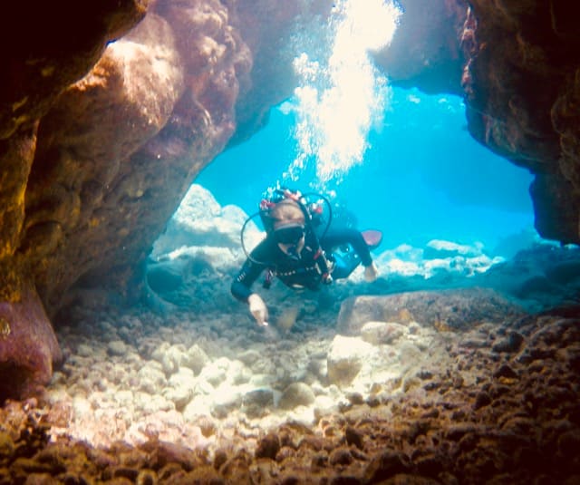 diver swims through skylight in cavern