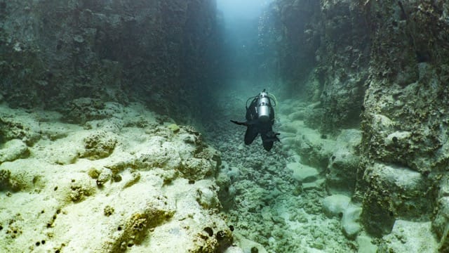diver swims in a lava canyon
