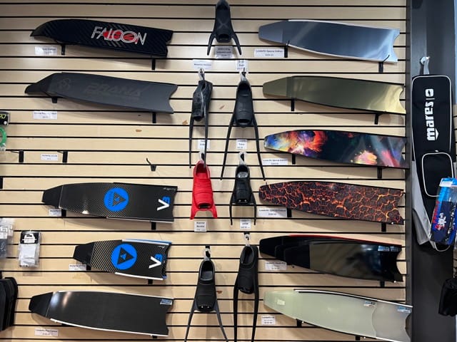 a wall in a dive shop with fin blades on display
