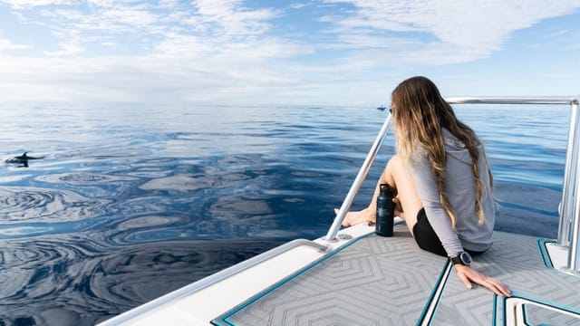 woman sits on the bow of a boat watching the water