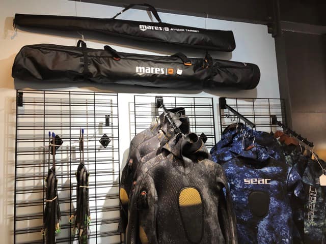 spearfishing wetsuits and gear hanging on wall inside of dive shop