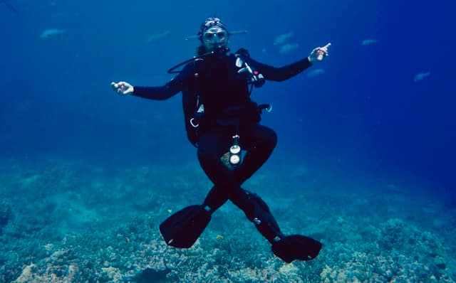 a diver hovers over the reef with legs crossed