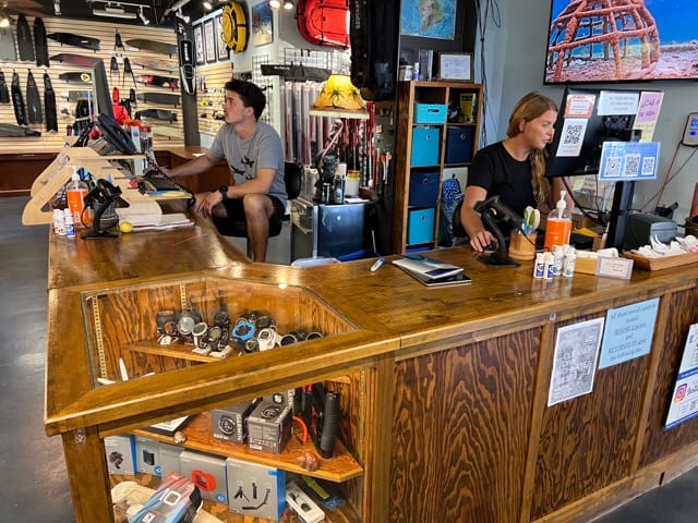 two people sitting at a counter inside a dive shop