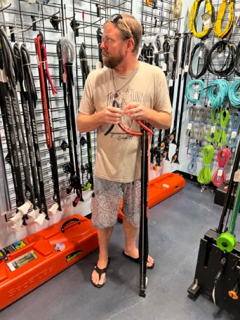 man standing with a speargun inside a dive shop