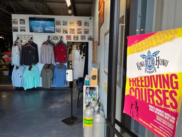 Dive shop entrance with blue cement floor and pictures on the wall with clothing on display