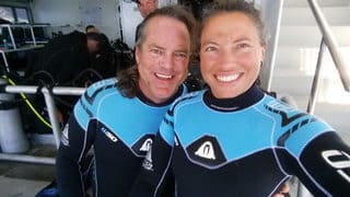 diver couple wearing same blue wetsuit taking selfie