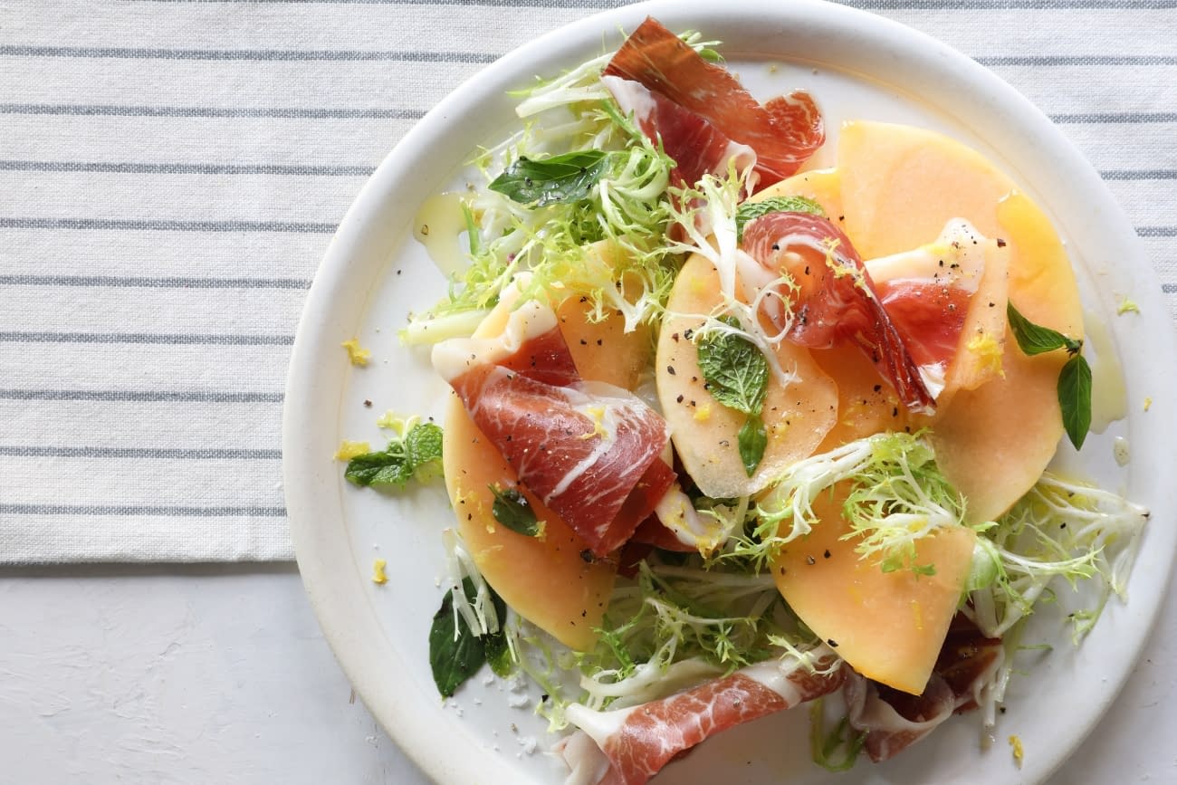 Melon con Jamon on a white plate: Melon with Iberian Ham and Fresh Herbs