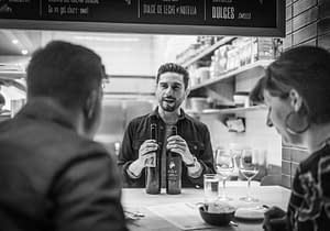 An employee of Boqueria talking to guests about two different Spanish wines.