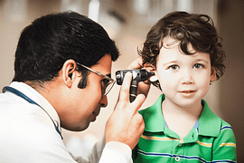 Doctor looking inside a child's ear with instrument