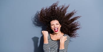 A woman fist pumping with her eyes closed and mouth open with a blue background