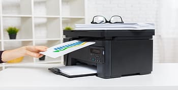 Hand of a person removing a printed piece of paper from a printer