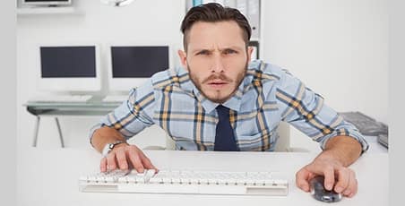 Man at computer keyboard looking at camera