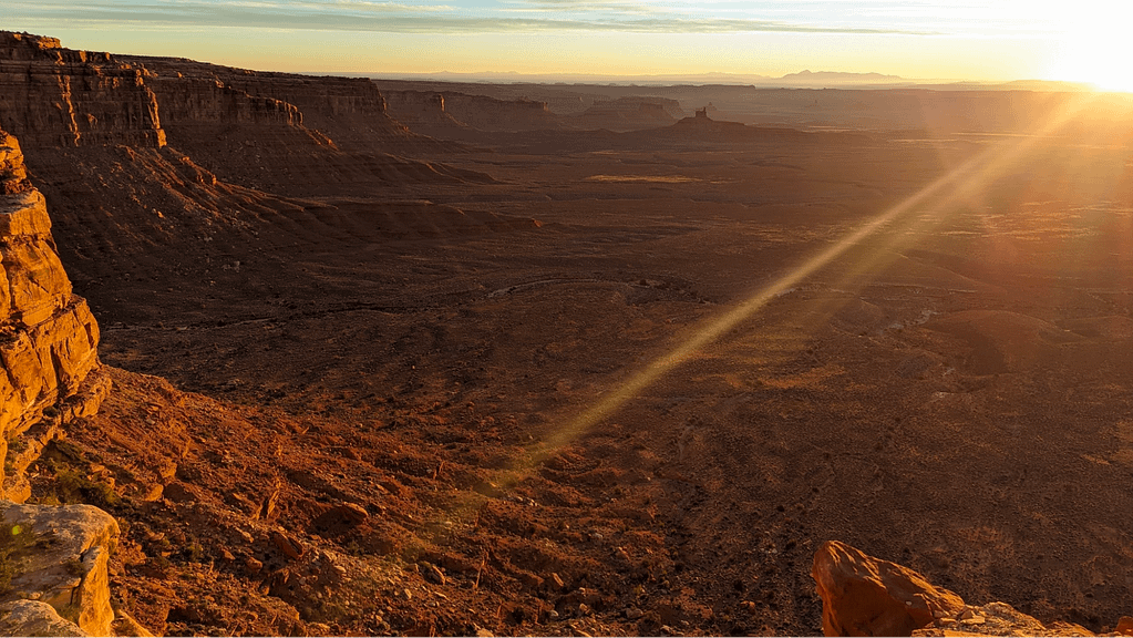 Rays of sunlight crack the horizon of a large landscape.