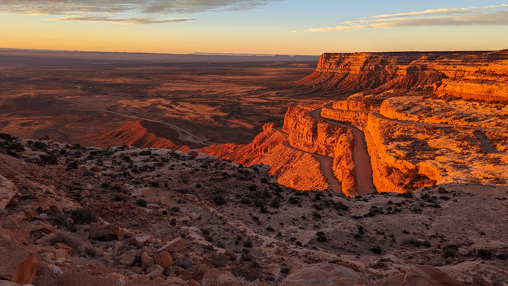 A rocky landscape with the rising sun illuminating cliffs.