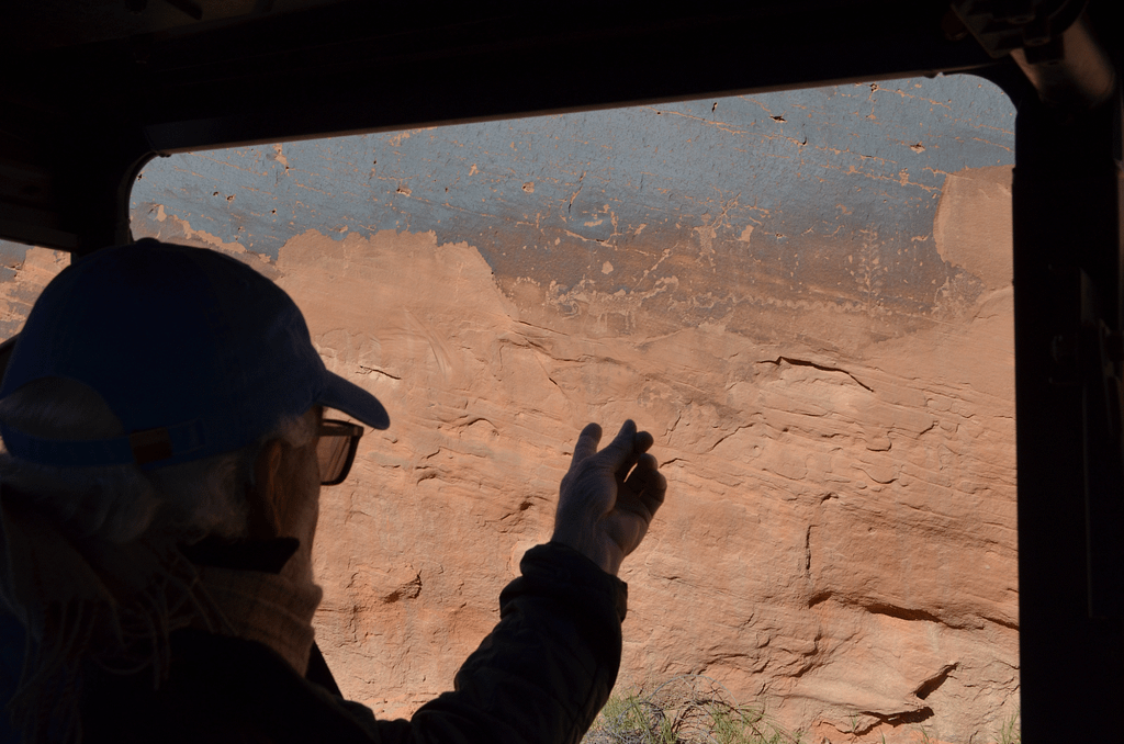Silhouette of a man pointing out petroglyphs in the canyon wall.