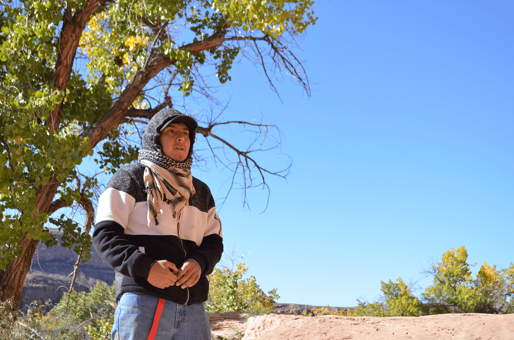 A man in front of tree, speaking.