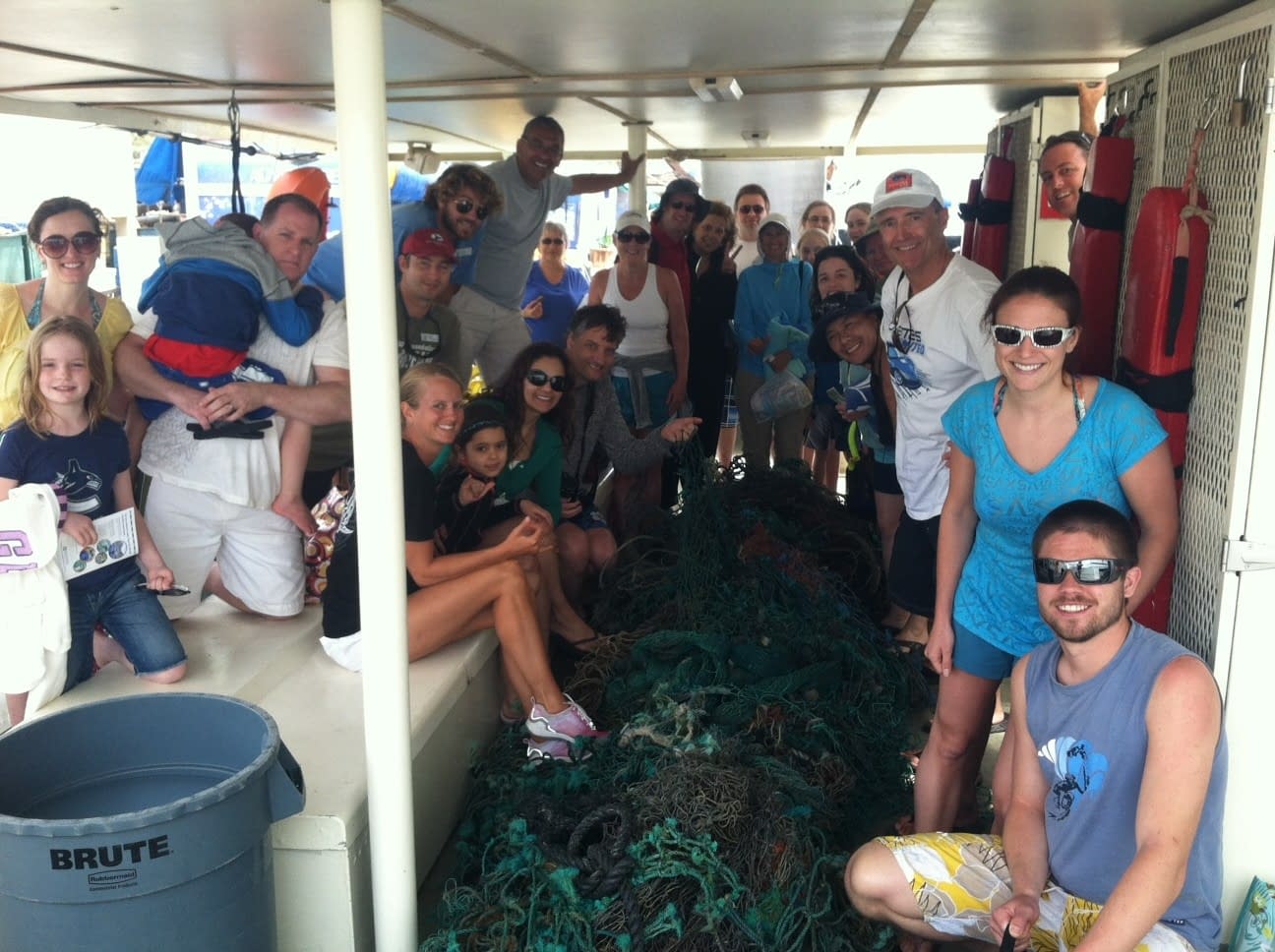 Pacific Whale Foundation guests and crew work together to remove a large net from the ocean during an Eco-Adventure