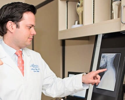 Head, neck, and spine specialist examining a patient’s neck x-ray at Azalea Orthopedics.