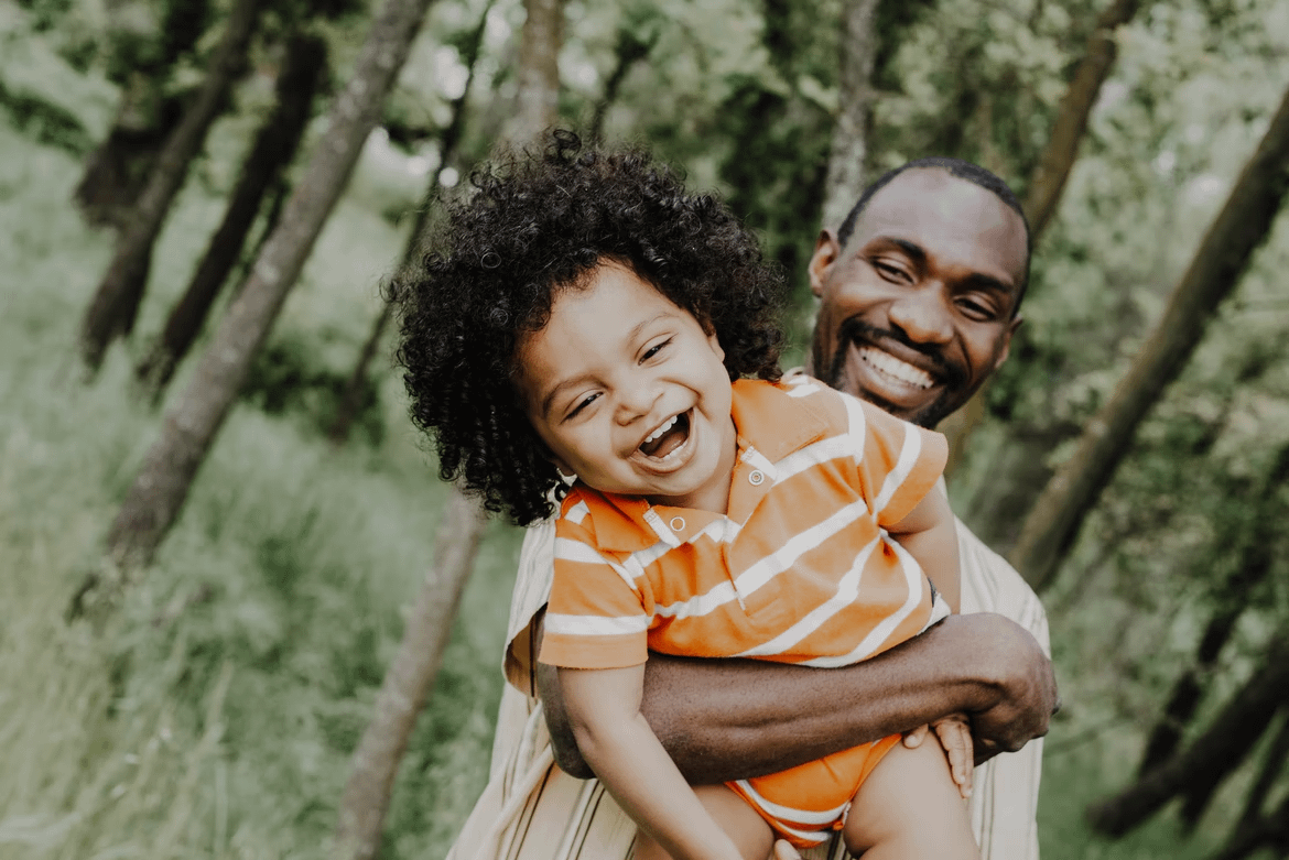 Black child laughing in father's arms