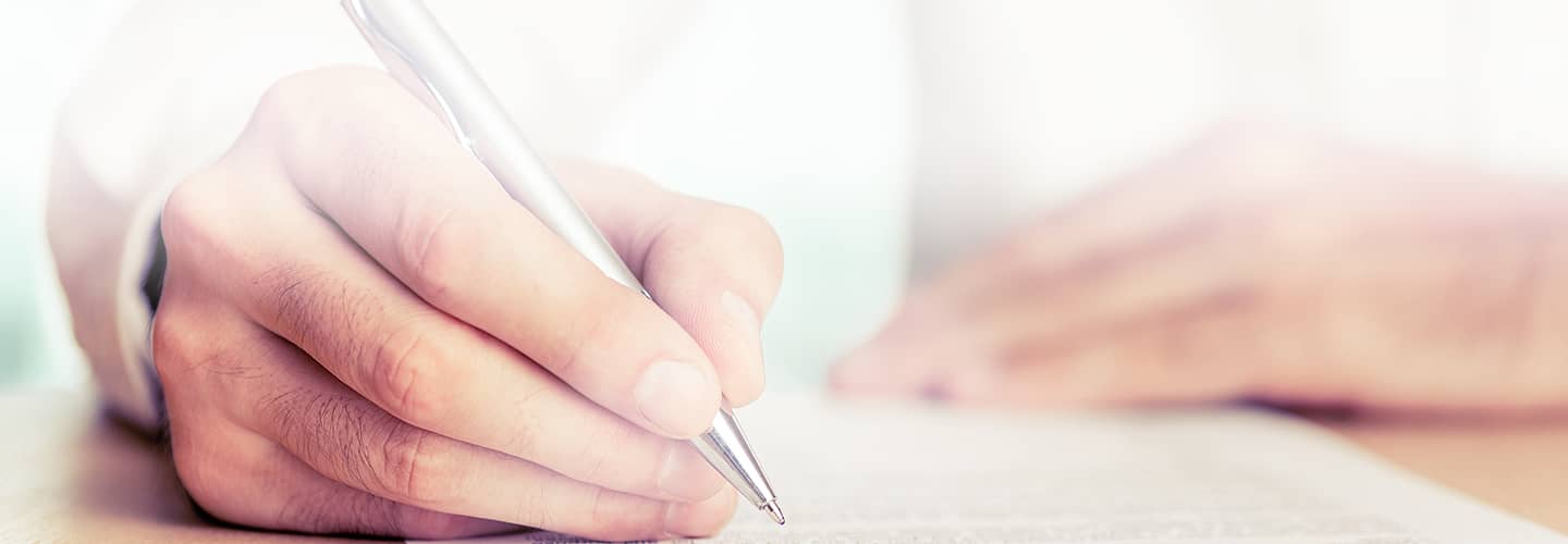 Close up of a patient signing a form with a pen.