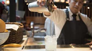 Bartender pours cocktail at Boqueria Spainish tapas bar during happy hour.
