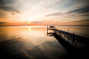 Sun setting over a lake dock during summer in Wisconsin.