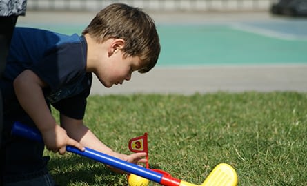 little boy setting a flag from a toy golf set