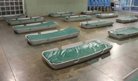 empty beds laid out inside a shelter