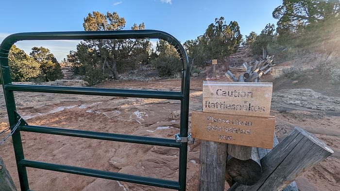 Closed gate at a trailhead with a sign that says "Caution Rattlesnakes"