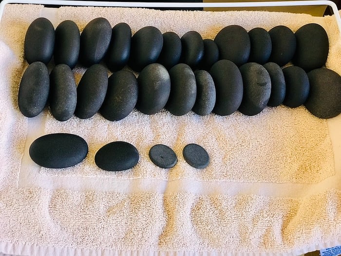 Smooth, black river stones lined up on a towel in preparation for a treatment