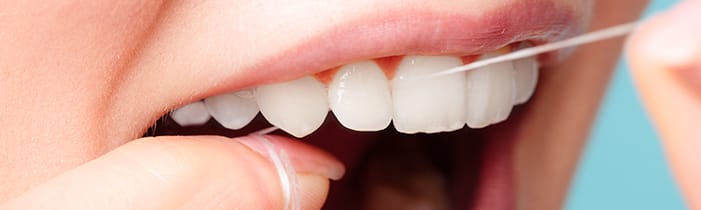 Close-up of person flossing teeth with dental floss, promoting daily oral hygiene habits and preventive dental care for healthy gums and plaque removal.